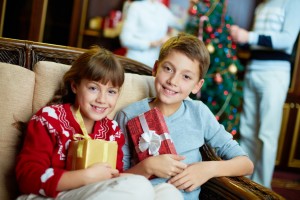 Dreng og pige sidder i sofa med deres julegaver