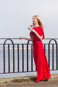 Kvinde med rose i hånden iført rød maxikjole