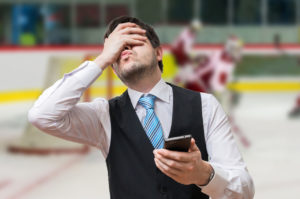 Ulykkelig mand med smartphone foran ishockey kamp - ludomani og gambling